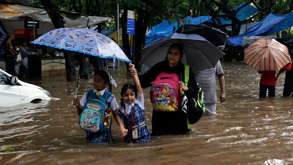 School children wade through a waterlogged street following heavy rains in Mumbai.