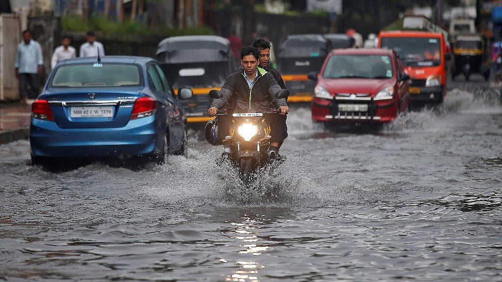 People commute through a water-logged road street after rains in Mumbai.