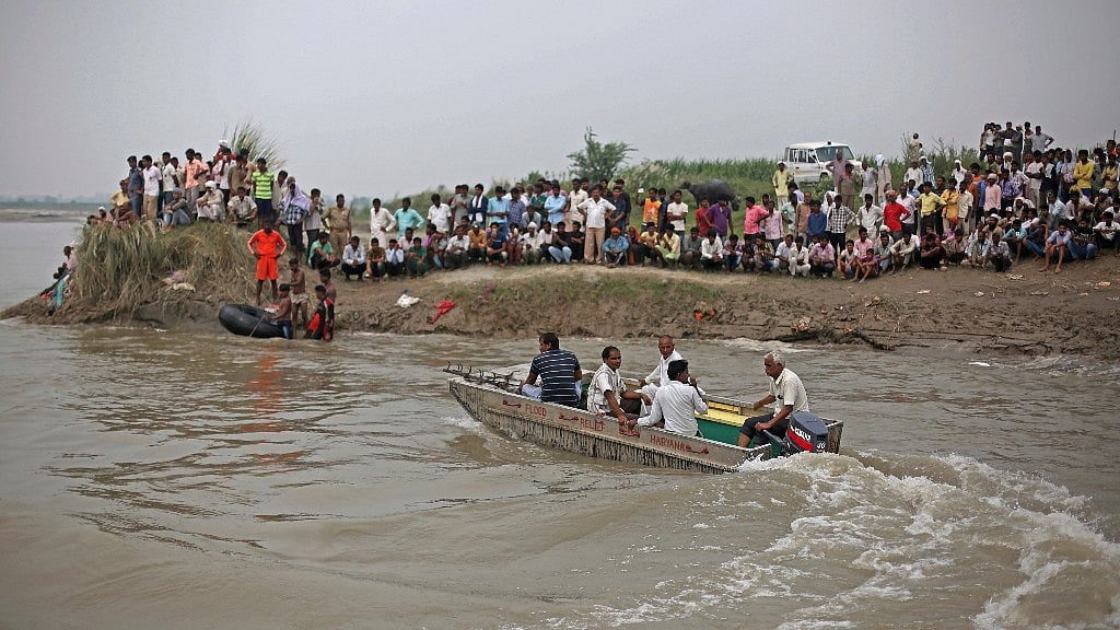 Rescuers search the Yamuna river as villagers after a boat capsized. 