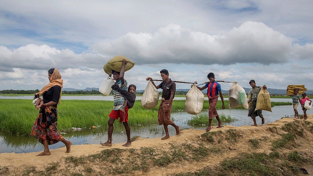 Rohingya Muslims, who spent four days in the open after crossing over from Myanmar into Bangladesh, carry their children and belongings after they were allowed to proceed towards a refugee camp, at Palong Khali, Bangladesh
