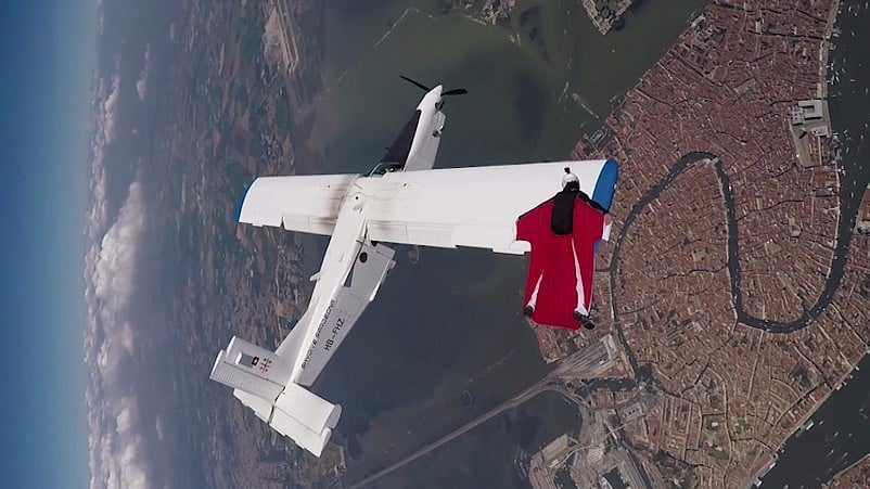 A man flies over a aircraft in a wingsuit, in Venice. <i>(Screenshot: AP)</i>