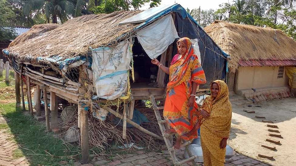 Women who remain on the island after the men migrate take shelter in a stilt house during floods.