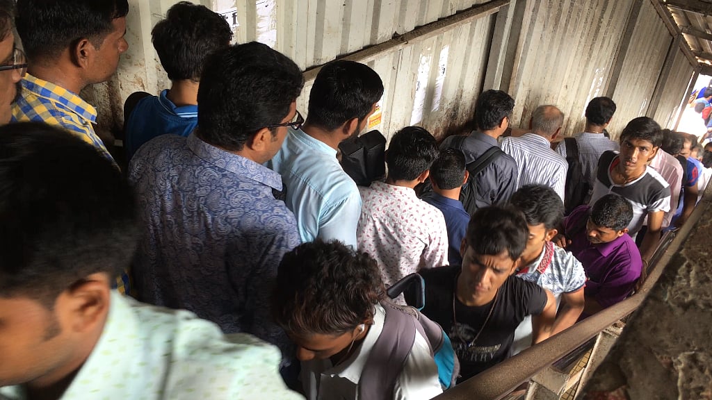 Commuters walk on a narrow bridge at the Parel station. 