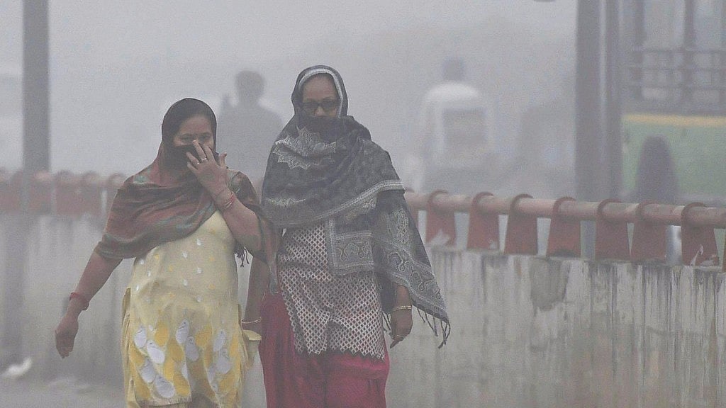 Women cover their face while walking through dense smog in New Delhi on Wednesday. 