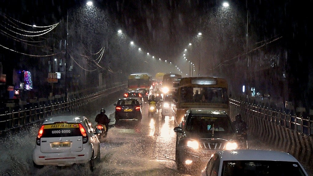 Vehicles move through a waterlogged road during heavy rain in Chennai. 