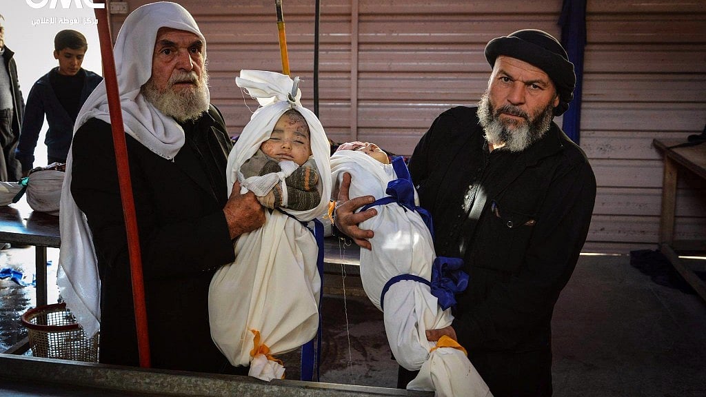 Syrian men carry two child bodies after a government airstrike hit Douma, near Damascus, Syria on 17 November, 2017.