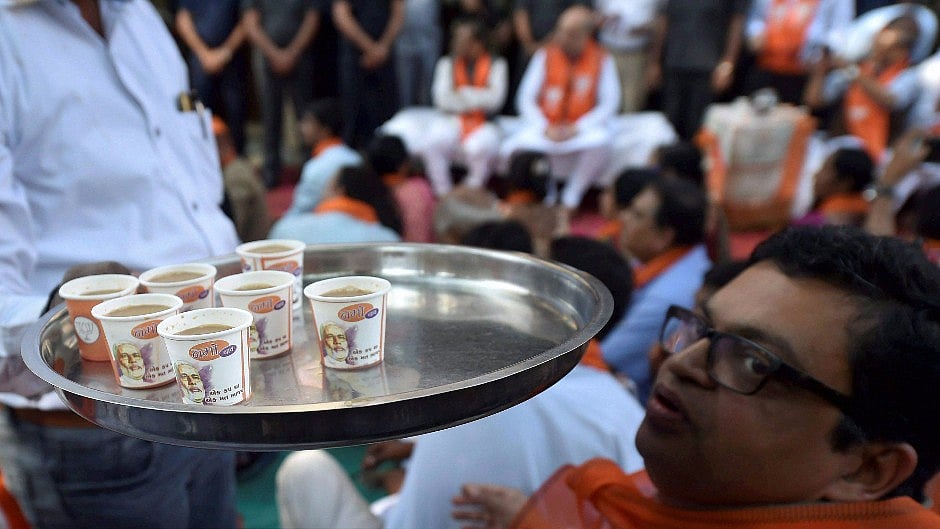 A BJP worker serves Namo Chay (tea) as BJP National President Amit Shah along with party leaders and workers listen to Prime Minister Narendra Modi’s “Mann Ki Baat”.