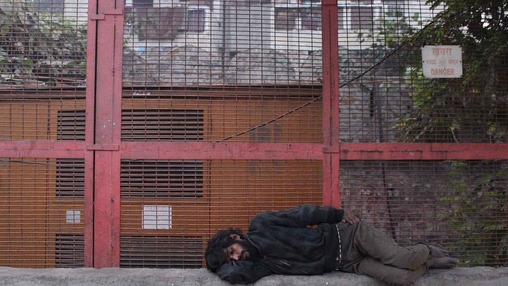 A homeless man sleeps out in the open next to a generator in Delhi’s Kashmere Gate.