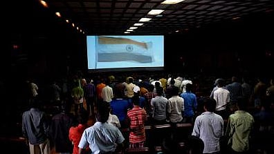 People stand for the national anthem at a movie hall. 