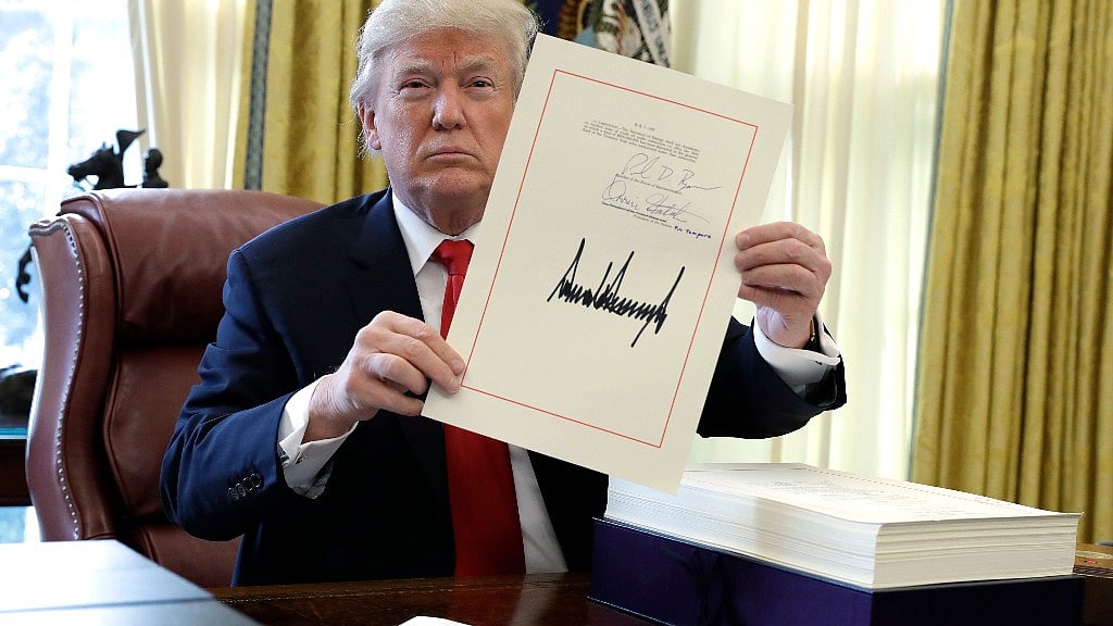 President Donald Trump displays the $1.5 trillion tax overhaul package he signed in December 2017 in the Oval Office of the White House in Washington. 
