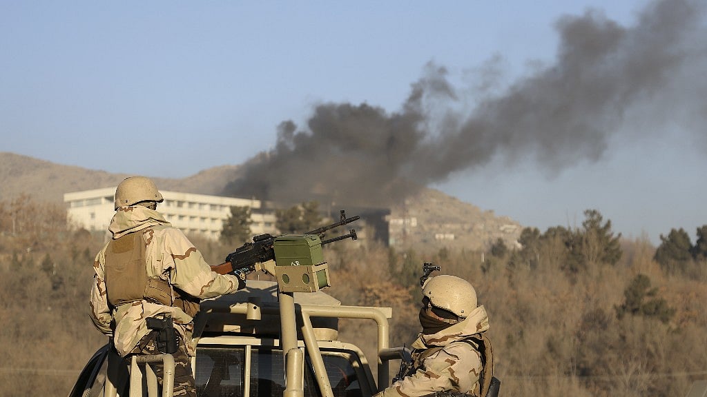 Afghan security personnel stand guard as smoke rises from the Intercontinental Hotel after the attack in Kabul.