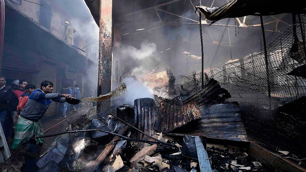 Locals and firefighters try to douse the flame after a fire at Gora Bazar of Dumdum Cantonment area.