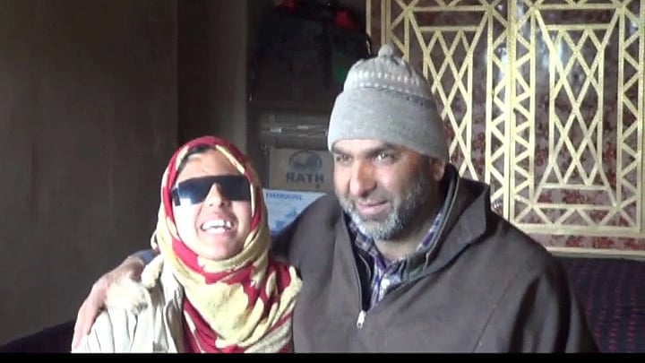 15-year-old Insha Mushtaq poses for a photograph with her father after clearing her 10th board exams.