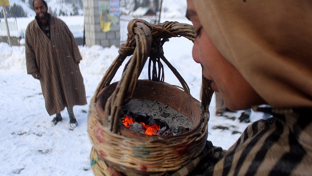 A boy blows a <i>kangri –</i> the traditional fire pot used by Kashmiris during winter to keep themselves warm. 