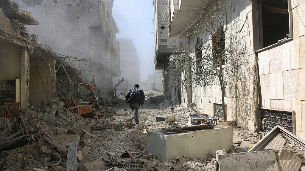 A Syrian man runs between destroyed buildings which attacked during airstrikes and shelling by Syrian government forces, in Ghouta, a suburb of Damascus, Syria.