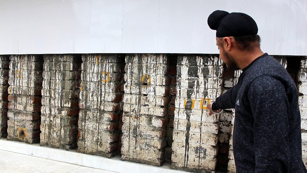 A victim’s family member shows bullet marks on the wall where the 36 Sikhs killed.