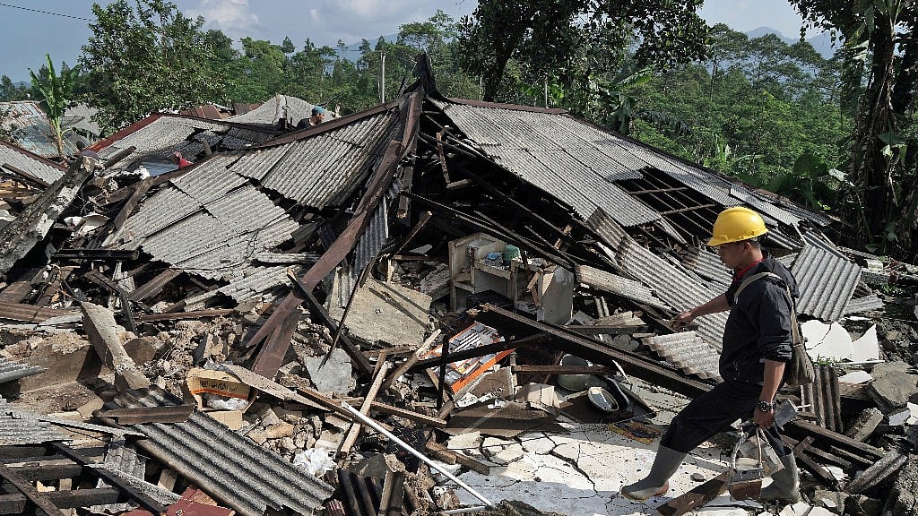 A rescuer walks on the rubble of houses in an area affected by an earthquake in Kalibening, Central Java, Indonesia, Thursday, 19 April 2018. 