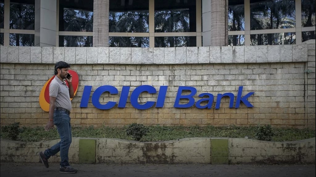 A man walking past an ICICI Bank branch.