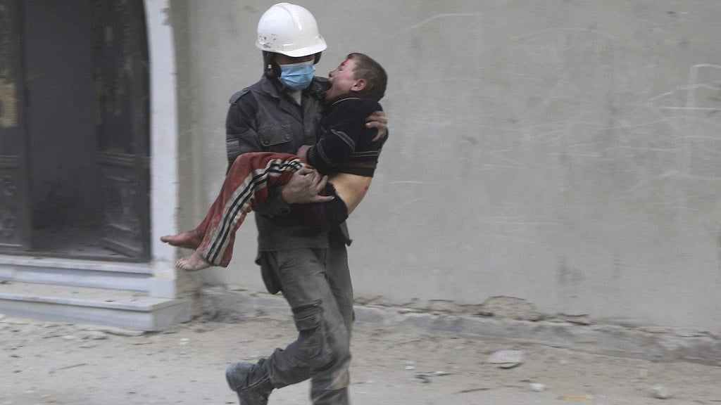 A member of Syrian Civil Defense group, the White Helmets, carries a boy who was wounded during airstrikes and shelling by Syrian government forces, in Ghouta,  Syria.&nbsp; Image used for representative purposes.