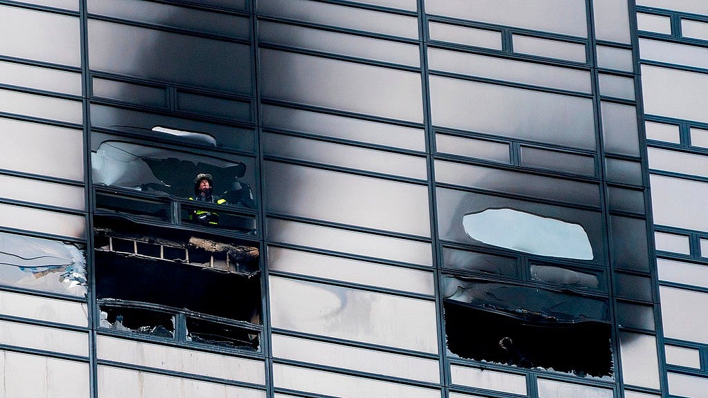 A firefighter looks out from the window of a damaged apartment in Trump Towers in New York on Saturday.
