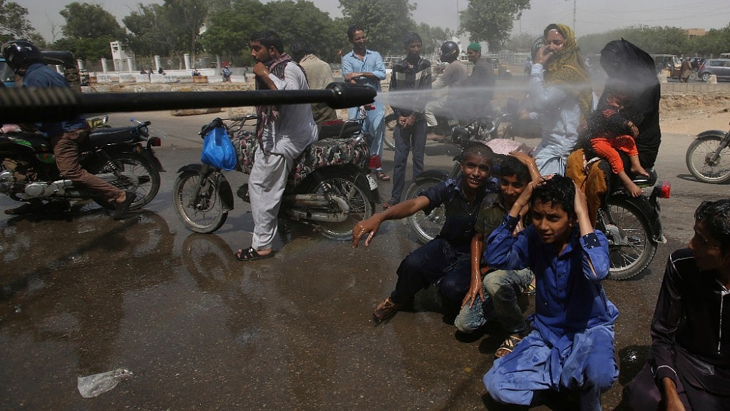 Pakistani volunteer spray water on people to keep them cool as temperatures reached 43 degrees Celsius in Karachi. 