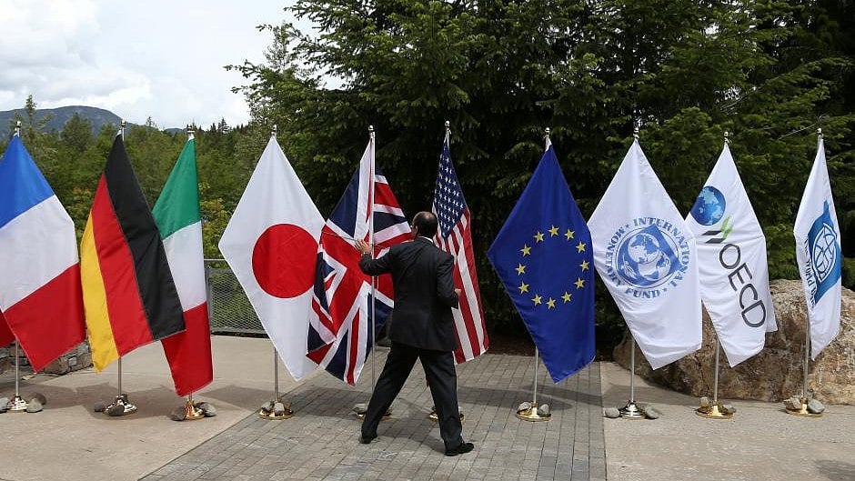 A delegate grabs a flag to prevent it from being blown over by the wind outside of the G7 Finance Ministers summit in Whistler, British Columbia, Canada.
