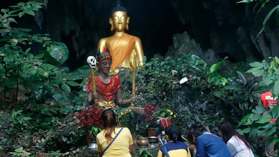 Family members pray in front of a Buddhist statue near the cave where 12 boys and their soccer coach had been trapped. 