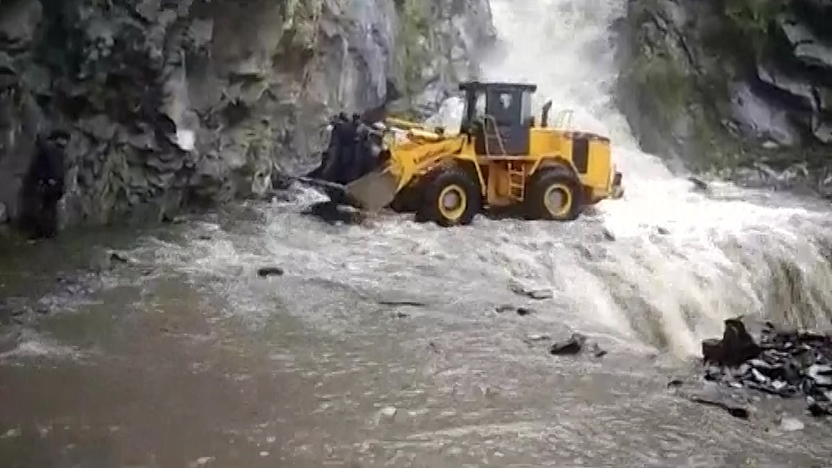 An earth digger takes the villagers across the flooded rivulet.