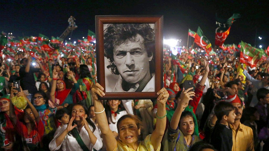 In this 22 July, 2018, file photo, a woman supporter of Tehreek-e-Insaf party raises a picture of her party’s leader Imran Khan during an election campaign rally in Karachi, Pakistan.