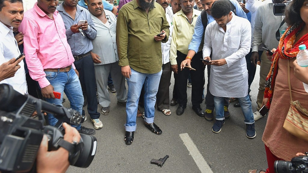 People gather near the pistol allegedly used to attempt a shot at Umar Khalid by an unidentified man at the Constitution Club near Parliament, in New Delhi on 13 August. 