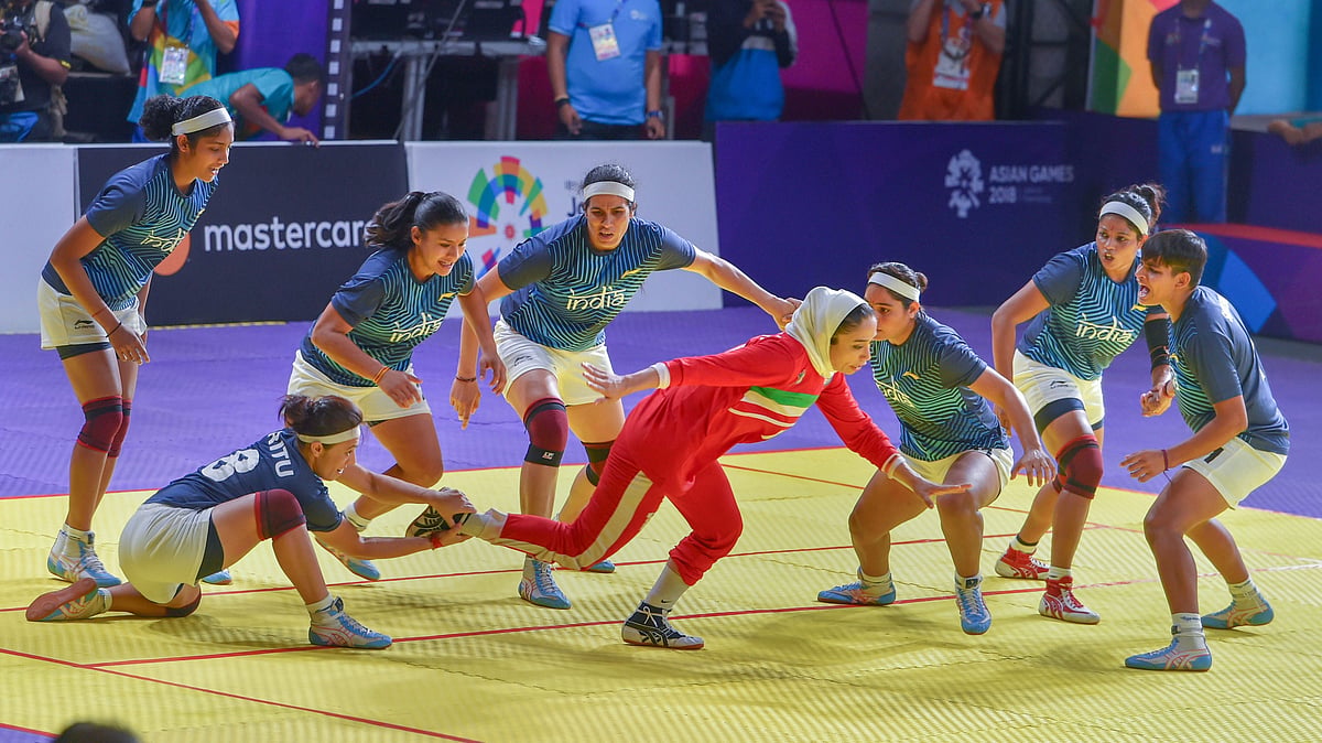 Indian women’s kabaddi team members tackle down an Iranian raider.