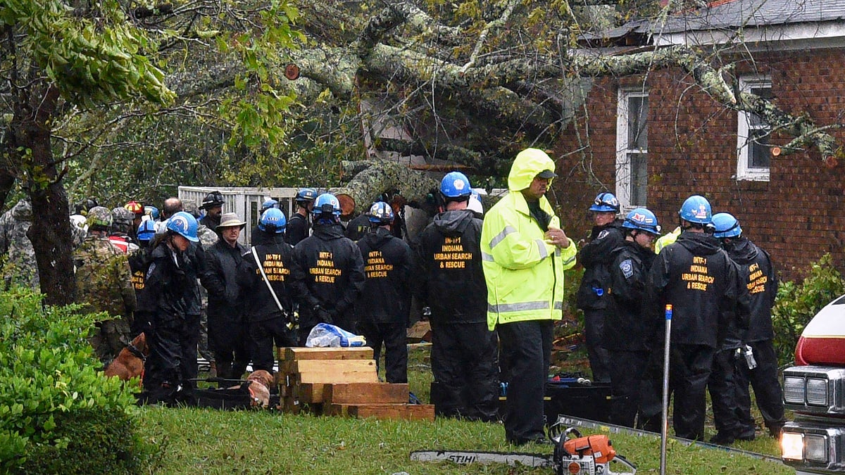 Rescue workers, police and fire department members wait to remove the bodies of a mother and child who were killed by a falling tree as Hurricane Florence made landfall in Wilmington.