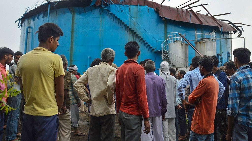 People stand near the site of explosion at a petro-chemical factory, where a methane gas boiler tank blasted killing six workers.