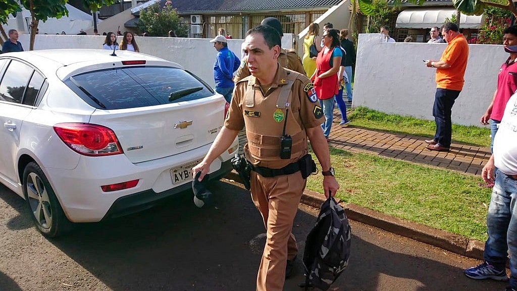 A police officer collects evidence at the scene of a shooting, at a school, in Medianeira, Parana state, Brazil, Friday, Sept.28, 2018.