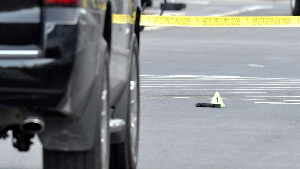 A gun lies on the ground next to an evidence marker outside of a Kroger Grocery in Jeffersontown.