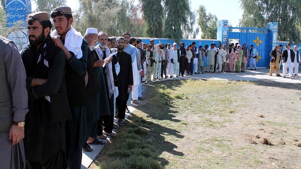 Afghan men line up to cast their votes, outside a polling station during the Parliamentary election in Helmand province, south of Afghanistan, Saturday, Oct. 20, 2018.