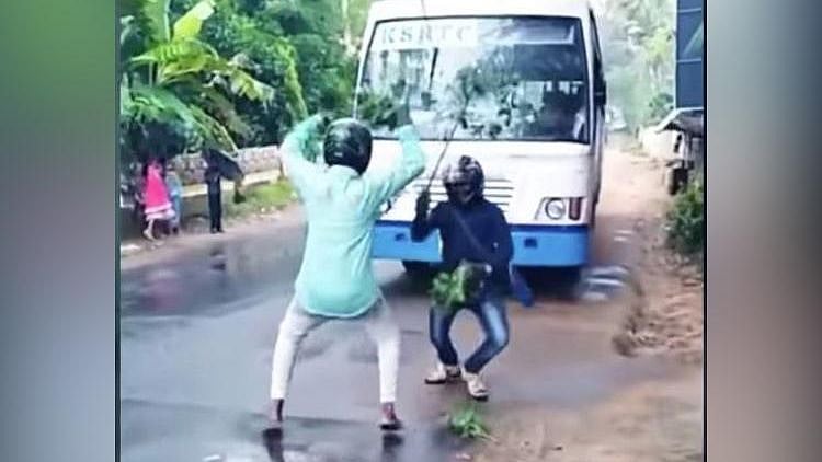 People dancing to the song in front of a moving bus wearing helmets, carrying dried leaves. 