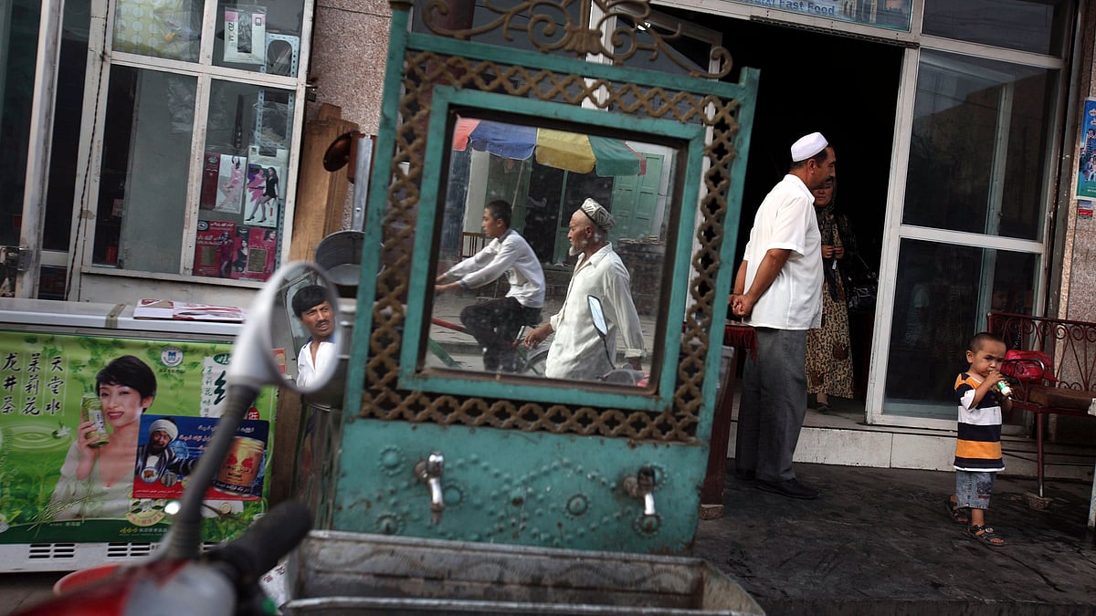 Uighurs are seen outside a restaurant in Kashgar in China’s western Xinjiang province. More than a million Chinese civil servants have been assigned to move into the homes of Uighurs and other ethnic minorities, spending weeks as uninvited guests.