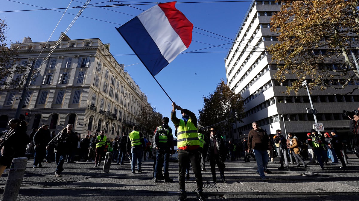 A demonstrator waves the French flag during a ‘Yellow Vest’ march on Saturday, 8 December, in Marseille, southern France. 