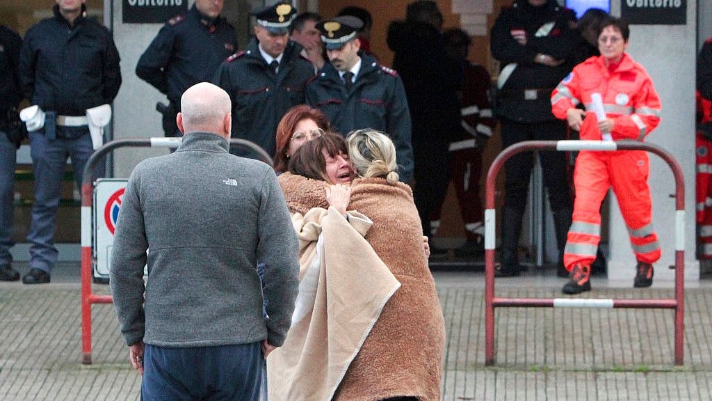 Relatives and friends comfort each others outside the morgue in Corinaldo, central Italy, Saturday.
