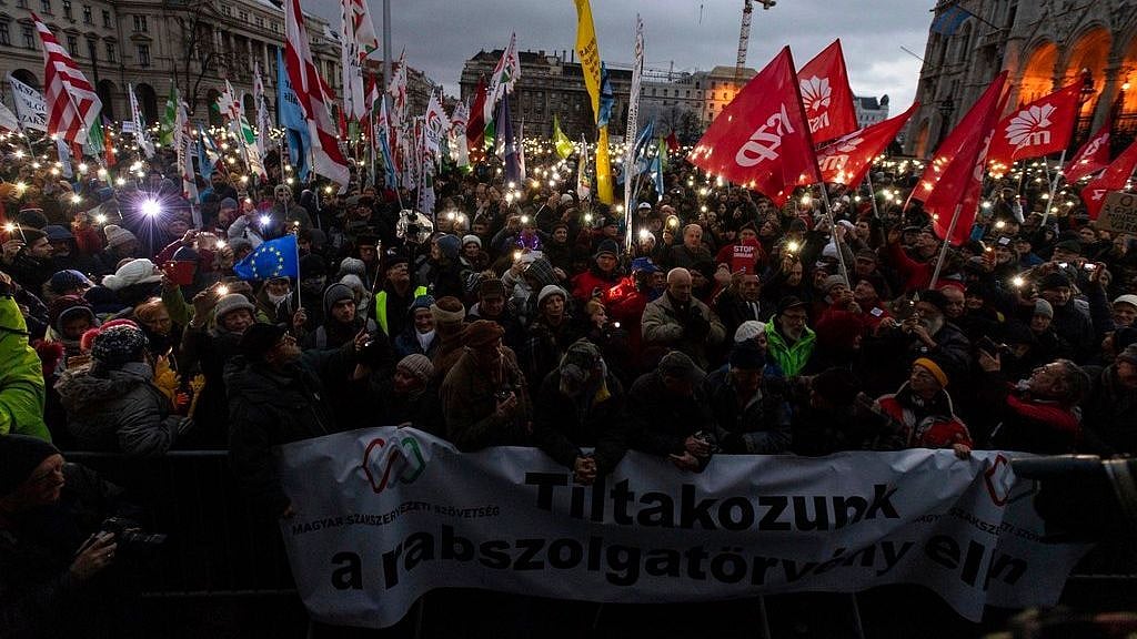 Anti-government demonstrators carry a banner reading “We protest against the slave bill” as they gather in front of the Parliament building at Kossuth square, downtown Budapest, Hungary.