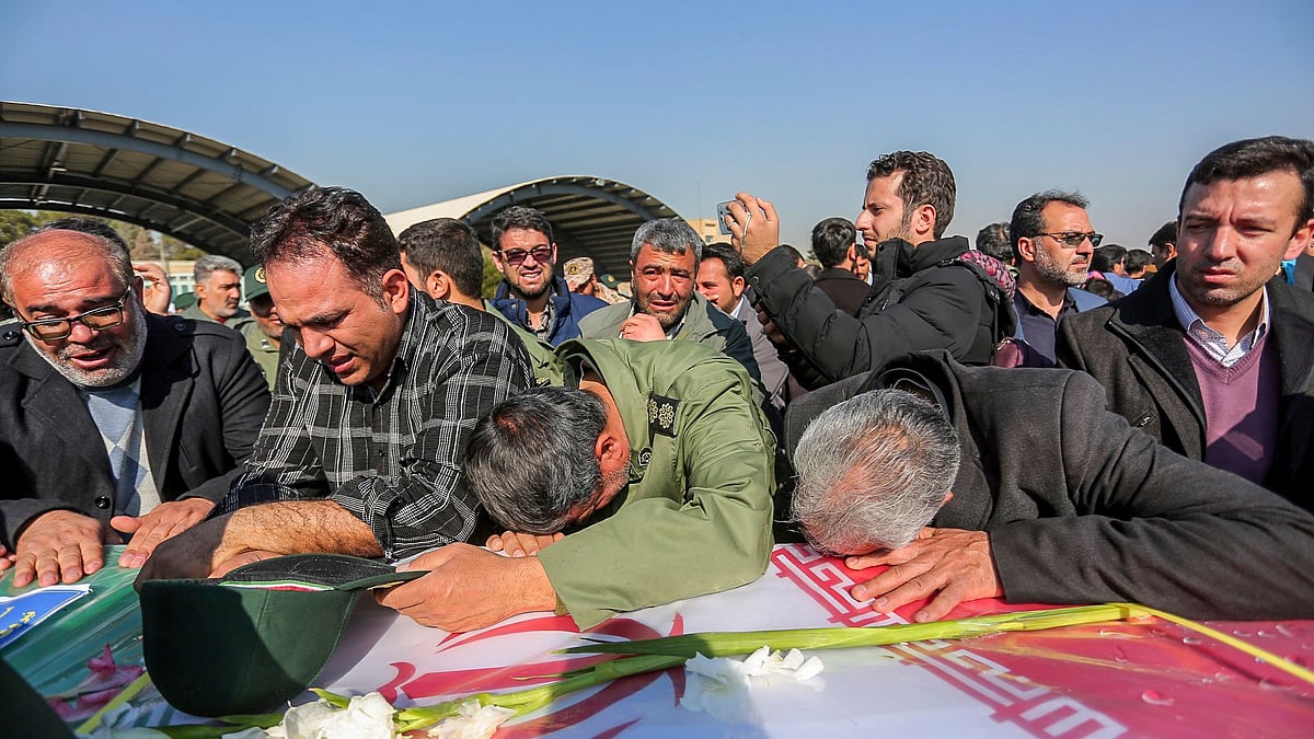 Mourners weep over a flag-draped coffin of a member of Iran’s Revolutionary Guard who was killed in a suicide car bombing that struck a bus carrying the Guard troops, killing at least 27 people on Wednesday, 13 February.