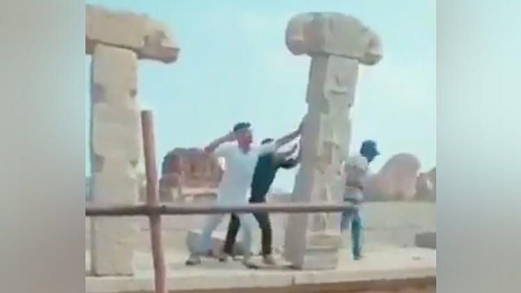 Men vandalising a pillar in Hampi