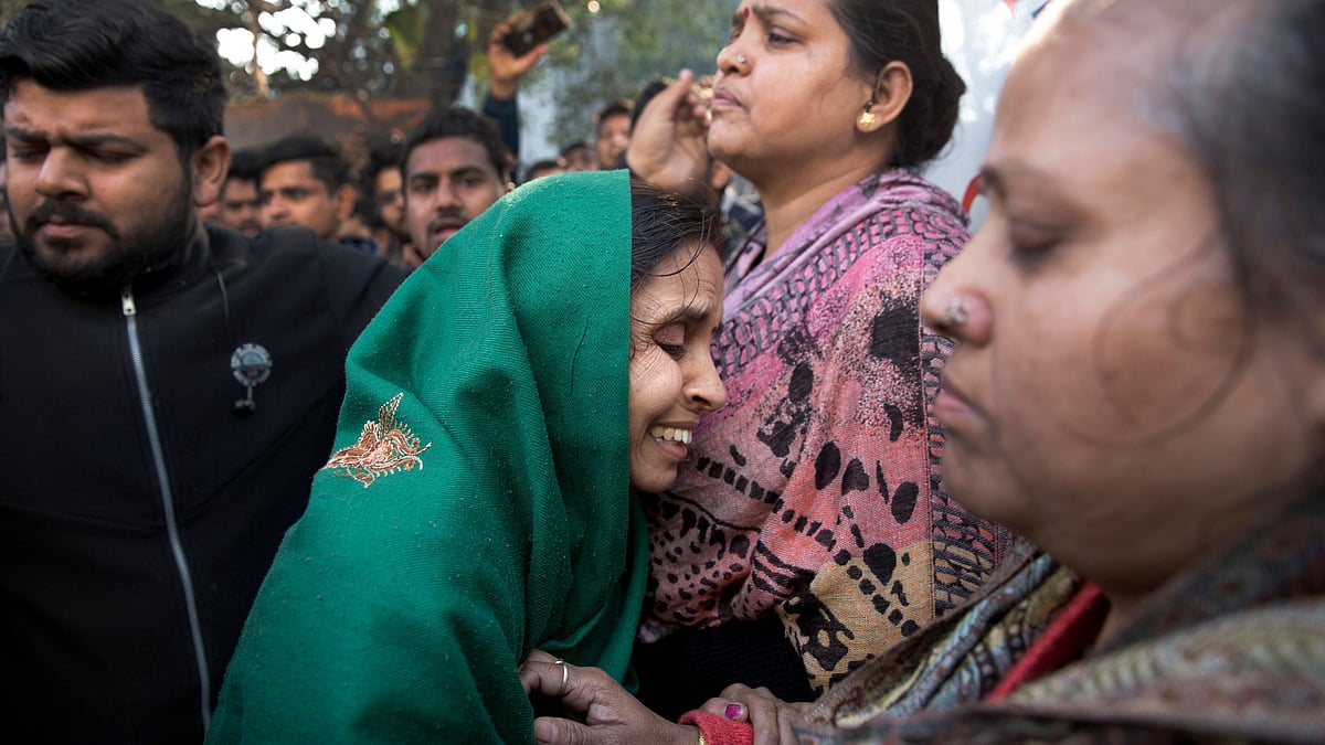 Unidentified relatives gather outside after an early morning fire killed more than a dozen people at a hotel in the Karol Bagh.&nbsp;