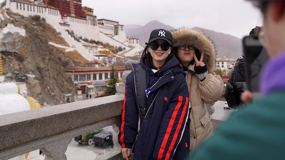 In this photo released by Xinhua News Agency, tourists pose for souvenir photos in front of the Potala Palace in Lhasa, Tibet.