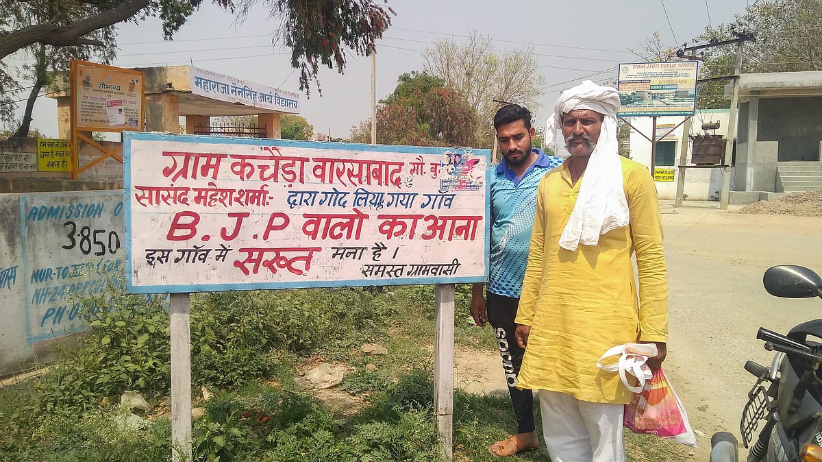 Villagers stand with the poster outside Kachera.