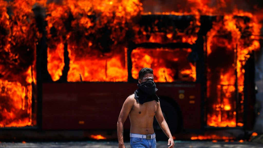 An anti-government protester walks near a bus that was set on fire by opponents of Venezuela’s President Nicolas Maduro during clashes between rebel and loyalist soldiers in Caracas, 30 April 2019. 