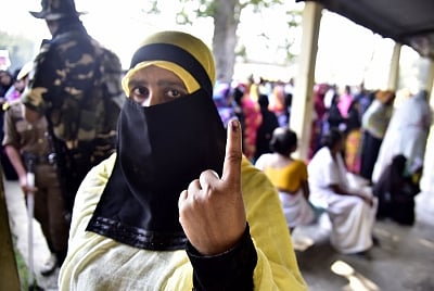 A Muslim woman shows her inked finger after casting vote.