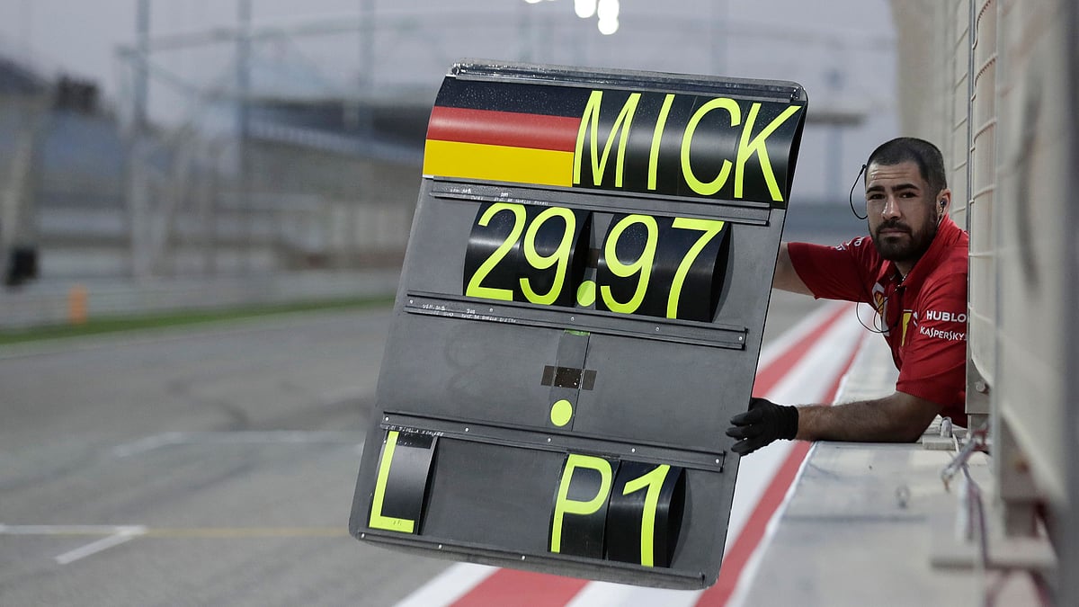 A Ferrari team member shows a pit board to Mick Schumacher during his first F1 test for Ferrari at the Bahrain International Circuit in Sakhir, Bahrain, Tuesday, April 2, 2019.&nbsp;