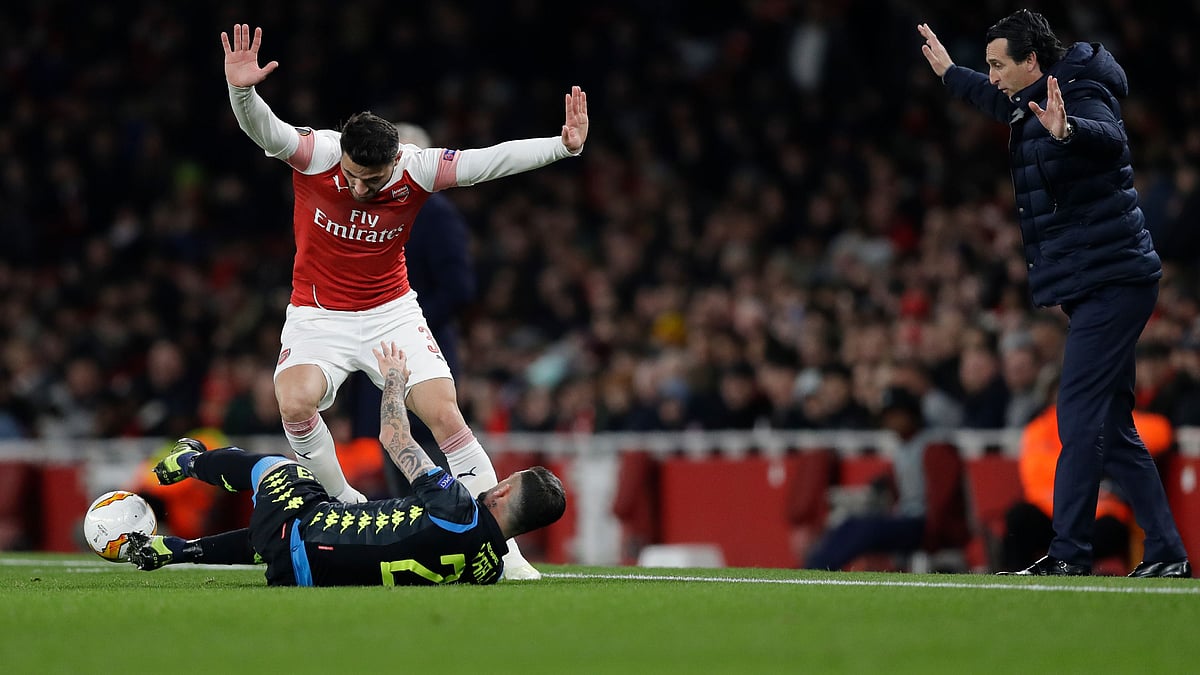 Arsenal’s Sead Kolasinac, top, raises his hands, along with Arsenal’s manager Unai Emery, right, after tackling Napoli’s Elseid Hysaj during the Europa League first leg quarterfinal.